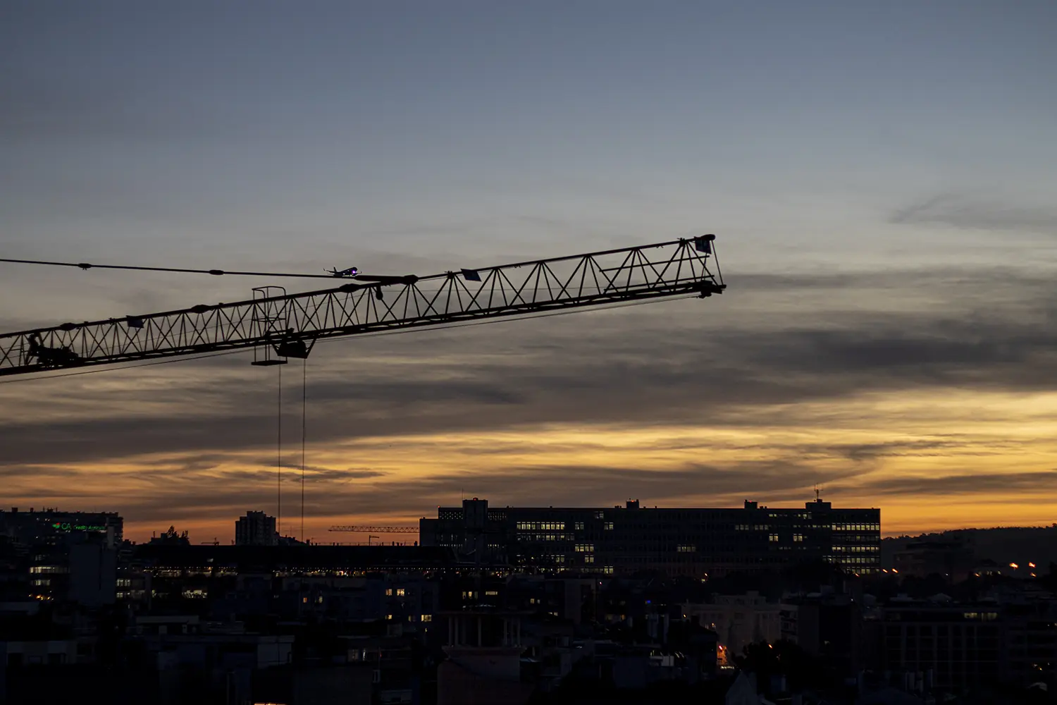 A view of the city of Lisbon with a crane and an aeroplane flying past in the background